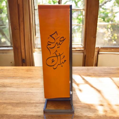 ستاند حديد مزين بعبارة ( عيدكم مبارك ) باللون البن...