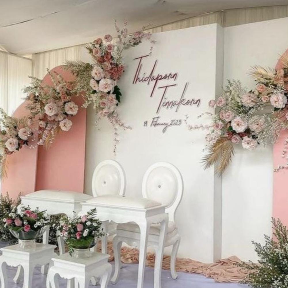 كوشة باللونين الوردي والأبيض مزينة بالزهور وكراسي وطاولات أنيق