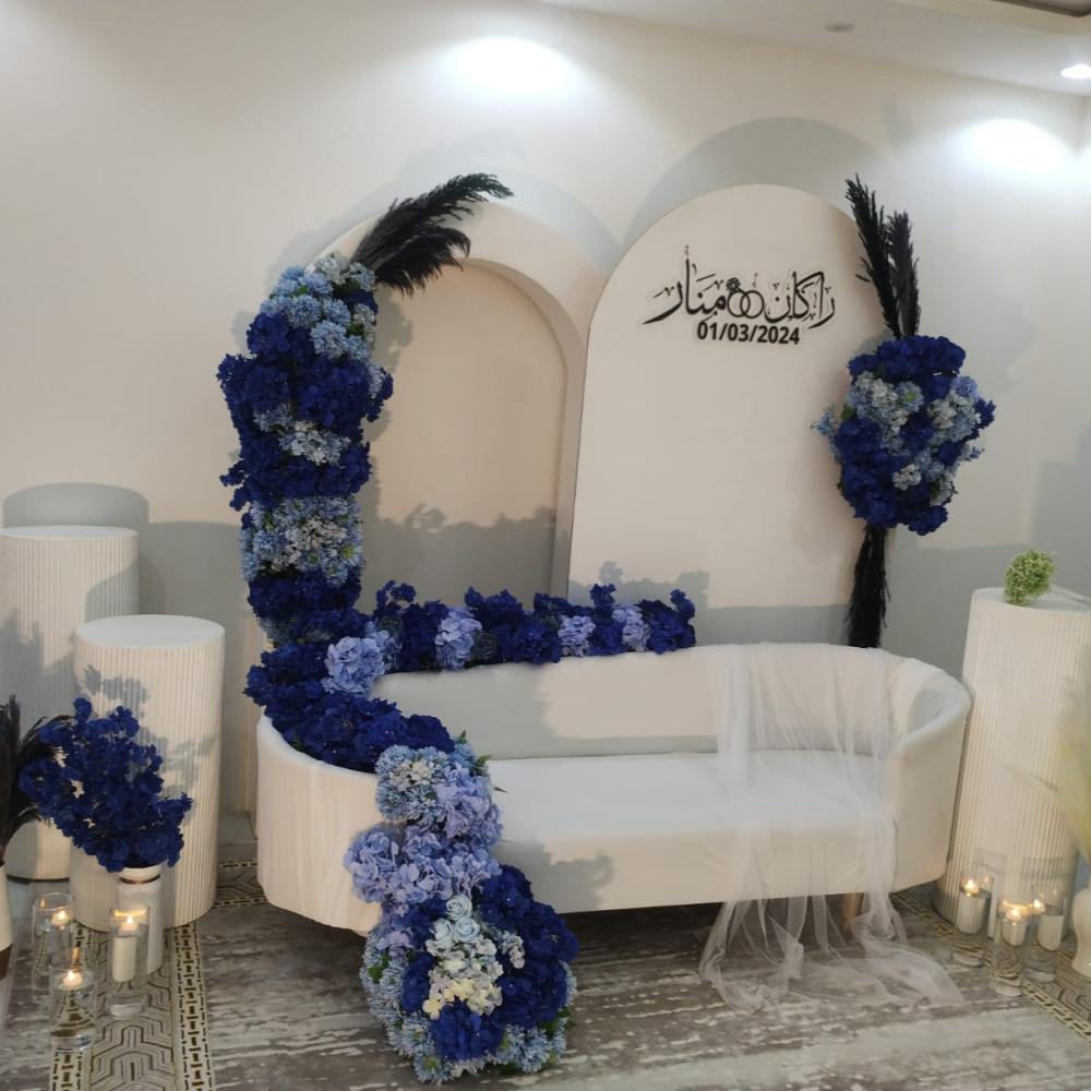 كوشة زفاف  كراسي بيضاء مزينة بالزهور البنفسجية مع أسماء العرسان