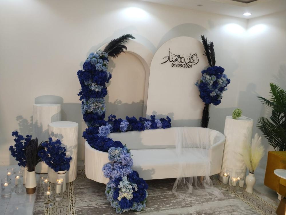 كوشة زفاف  كراسي بيضاء مزينة بالزهور البنفسجية مع أسماء العرسان