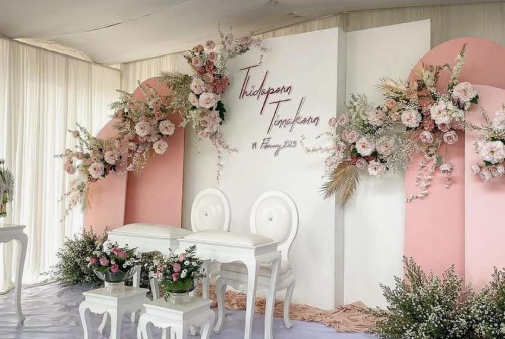 كوشة باللونين الوردي والأبيض مزينة بالزهور وكراسي وطاولات أنيق