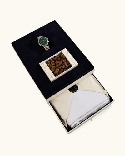 A men's gift set containing a piece of oud, a watch, and a cloth.