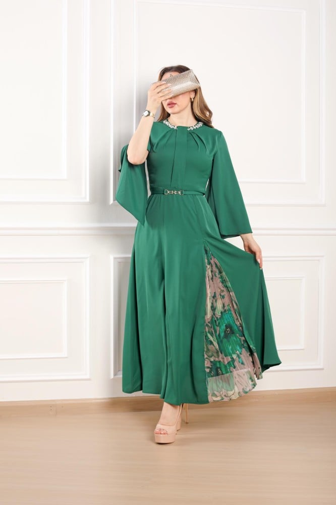 Long green dress with long sleeves and an accessory at the neck