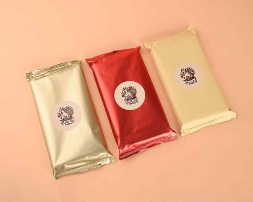 لوح شوكولاتة ذهبي اللون في يد مرتدية قفاز أسود