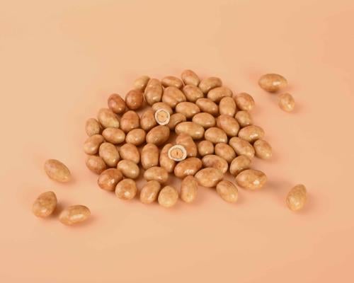 حبات فول سوداني بالكراميل لامعة في ملعقة تقديم