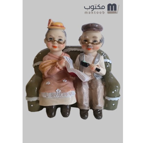 دمية رجل و امرأة عجوز على كرسي مع كتاب