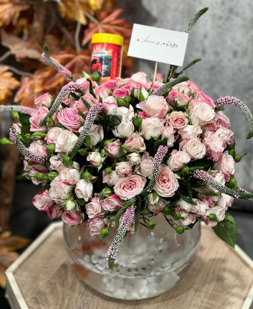 زوج من أسماك الزينة مع احجار الزينة في فازة دائرية منسقة بورد بيبي روز baby pink واكسسوار الفيرونيكا