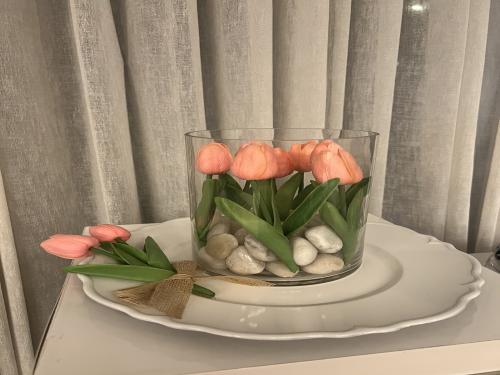 صحن تقديم  فوق مزهرية زجاج فيها ورد متوفر فقط لون زهري وصحن ابيض