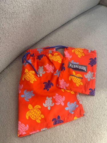 Red and blue print bathing suit with flip-flops and bath bag