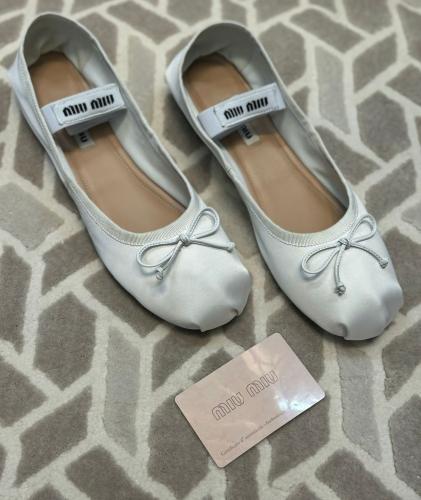 Women's flat white leather ballet shoes with a distinctive knot