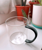A clear cup with a black handle