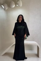 فستان أسود بتفاصيل خضراء لامعة بتصميم فاخر