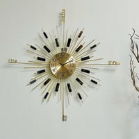 ساعة حديد ذهبي بشكل دائري واشعة الشمس بارقام سوداء...