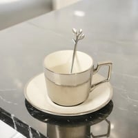 فنجان قهوة بتصميم انيق مع صحن و ملعقة لون ابيض وفض...