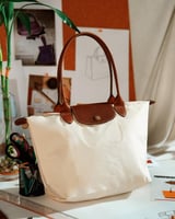 ‎ شنطة نسائية بحجم متوسط بلون بيج.