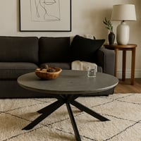 طاولة دائرية أنيقة بسطح رصاصي وقاعدة معدنية عصرية.