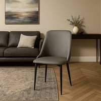 كرسي بتصميم ناعم ومبطن بجلد رمادي أنيق، وهيكل معدن...