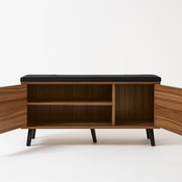 مقعد خشبي أنيق بوسادة سوداء ودواليب تخزين عملية.