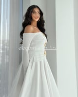 فستان أبيض أنيق بكتف ساقط وتفاصيل ذهبية