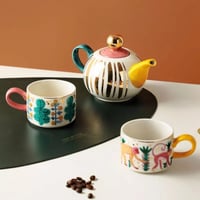 ابريق شاي مع كوبين بحافة ذهبية مرسومة يدويًا