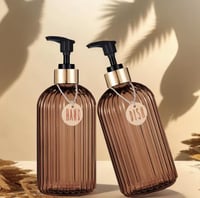 زجاجتين مضلعتين بلون العنبر، تحملان اسم "صابون الأ...