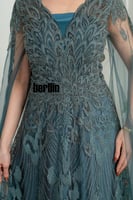 فستان سهرة طويل بترولي بتطريز ريش كثيف وأكمام كيب