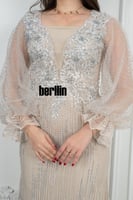 فستان سهرة أنيق بيج مزين بتطريز فضي فاخر وأكمام شف...