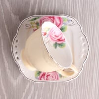 فنجان بيج مع صحن متعرج منقوش بالورود