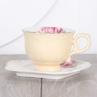 فنجان بيج مع صحن متعرج منقوش بالورود