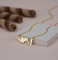 عقد يجمع-حرفين في بريق الذهب عيار 21.