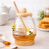 وعاء عسل زجاجي بتصميم خلية مع ملعقة خشب