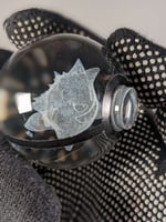 كورة بوكيمون زجاجية مع قاعدة مضيئة.