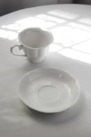 كوب مع صحن بتلات الزهور البيضاء