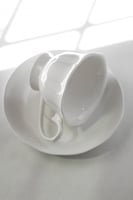 كوب مع صحن بتلات الزهور البيضاء