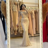 فستان سهرة ذهبي ضيق بترتر لامع وأكمام طويلة شفافة