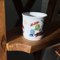 ‎كوب فنتج من السيراميك يحمل تصميمًا لشخصيات من مسل...