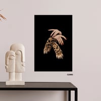 لوحة جدارية تصور يد فتاة وكف نمر بخلفية سوداء