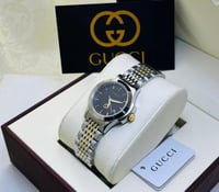 ساعة قوتشي فضي و ذهبي بإطار أسود شامل الملحقات