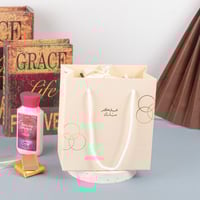 أكياس فاخرة للعيد لون بيج بدوائر ذهبية وختم "عيدكم...