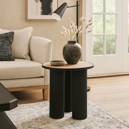 طاولة جانبية دائرية أنيقة بثلاث أرجل مخددة وسطح خشبي يعكس أسلوبًا عصريًا بسيطًا.