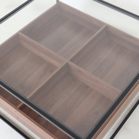 طاولة قهوة وسط بسطح زجاجي وقواعد معدن