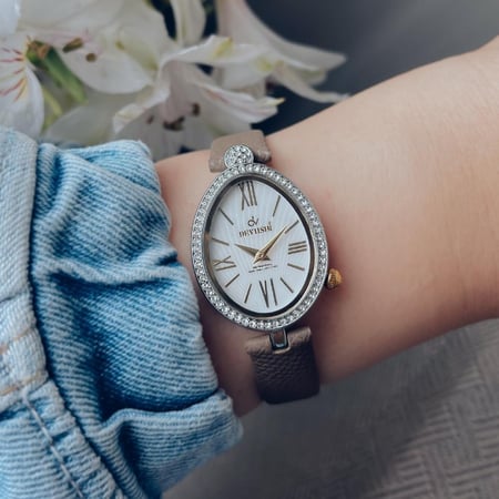 ساعة نسائية بتصميم مميز جلد بلون رمادي مؤشرات ذهبية اطار فضي ميناء ابيض