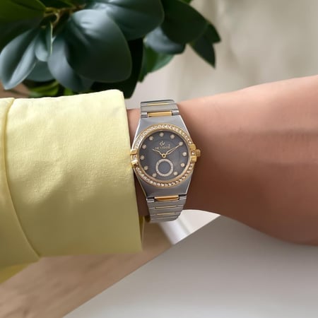 ساعة نسائية استيل بتصميم ملفت وحزام انيق لون ذهبي و فضي ميناء ذهبي ميناء رمادي