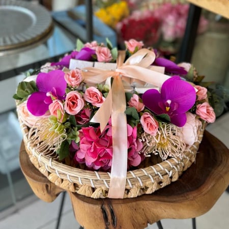 سلة ورد صناعي أنيقة مزينة بزهور ملونة مع شوكولاتة فاخرة للتقديم