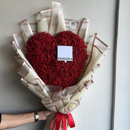 باقة أنيقة على شكل قلب مكونة من زهور حمراء مصممة بعناية مغلفة بورق فاخ