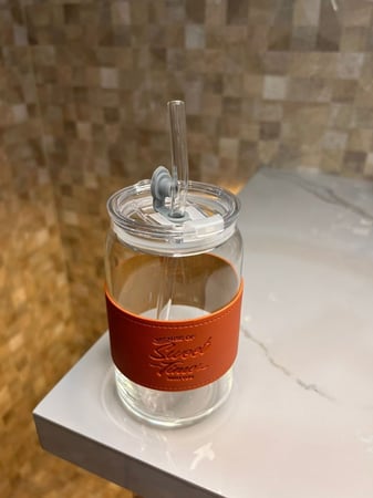 كوب زجاجي مع مصاص لون برتقالي