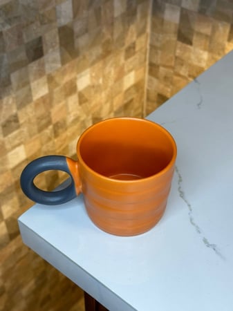 كوب سيراميك برتقالي بمسكه سوداء