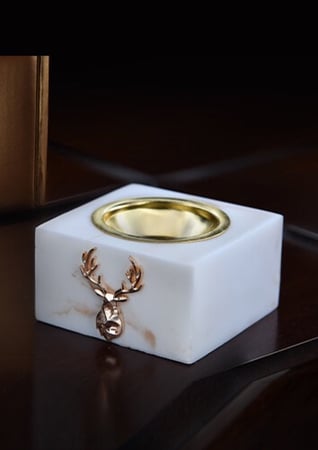 مبخرة من الرخام الابيض عليها شعار غزال ذهبي من متجر عاج الغزال