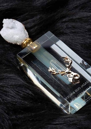 زجاجة مسك ابيض عليها شعار غزال معدني على فرو اسود من متجر مسك الغزال