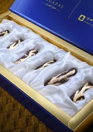 صندوق فاخر بعود مذهب مرتب في بطانة حريرية بيضاء مع شعار AJGAZAL الأنيق